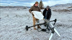 Photo of drone operators loading grass seed in a DJI T50 drone.